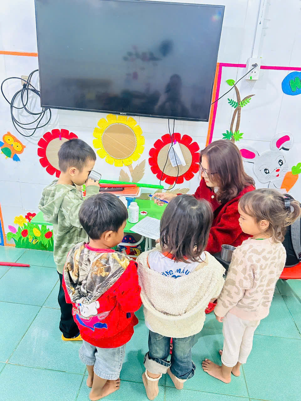 Hình ảnh nhân viên y tế trường học cho trẻ uống VTM A và thuốc sổ giun theo chường trình